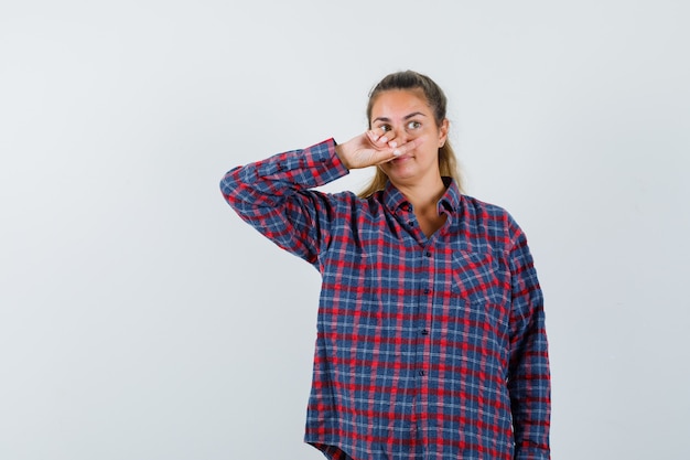 Foto grátis mulher jovem cobrindo a boca com a mão em uma camisa quadriculada e bonita