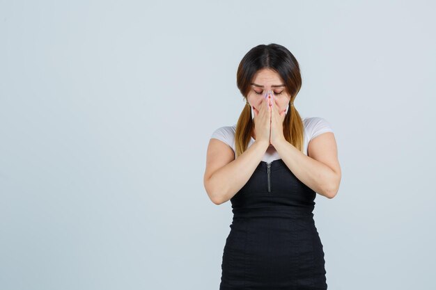 Mulher jovem com as mãos na boca em gesto de oração