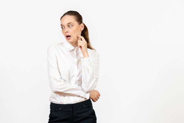 Mulher jovem com blusa branca e rosto nervoso no fundo branco. trabalho de escritório, emoções femininas, modelo de sentimento