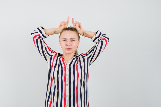 Foto grátis mulher jovem com blusa listrada, mostrando gesto de perdedor e parecendo triste