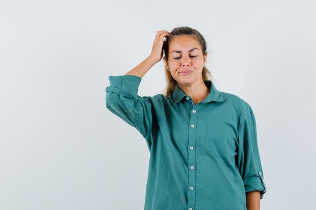 Foto grátis mulher jovem com blusa verde coçando a cabeça e parecendo pensativa