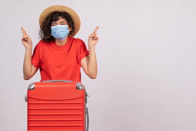Mulher jovem com bolsa na máscara esperando no fundo branco cor covidêmica - pandemia de vírus solar viagem turística