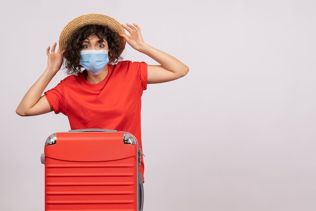 Mulher jovem com bolsa na máscara no fundo branco cor covid- voyage turista férias sol vírus viagem