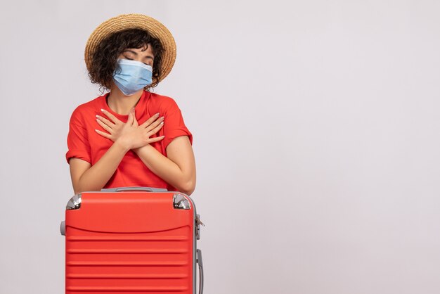 Mulher jovem com bolsa na máscara sobre fundo branco vírus covid - viagem colorida de férias de pandemia de turista