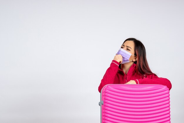 Foto grátis mulher jovem com bolsa rosa na máscara pensando na parede branca vírus de férias covid - pandemia de mulher de viagem de cor frontal