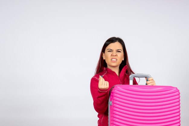 Mulher jovem com bolsa rosa na parede branca, vista frontal, emoção férias viagem voo viagem mulher