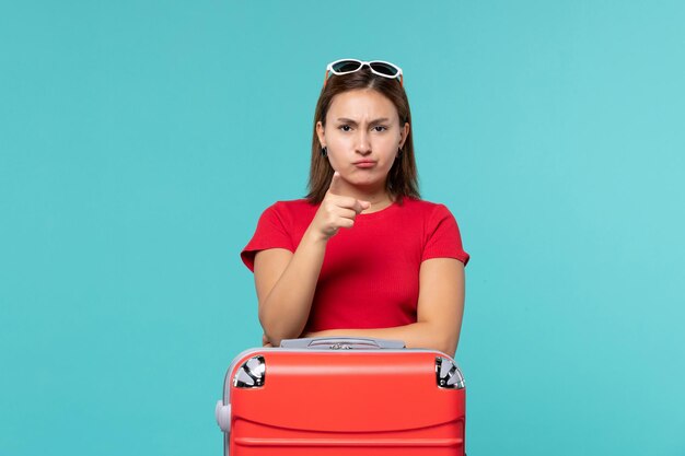 Mulher jovem com bolsa vermelha se preparando para as férias no espaço azul.