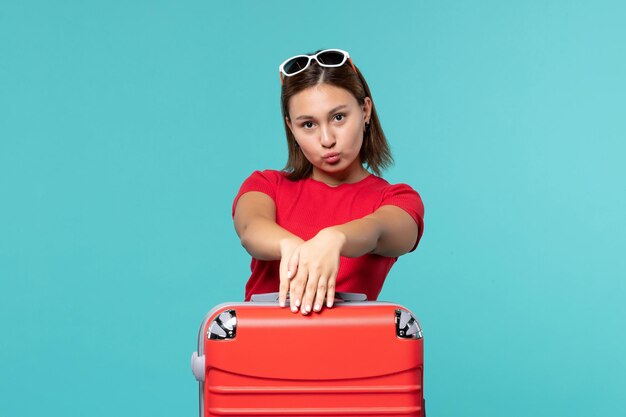 Mulher jovem com bolsa vermelha se preparando para as férias no espaço azul.