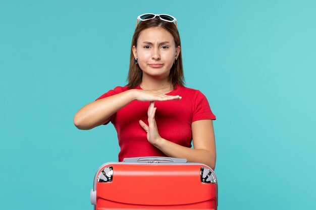 Mulher jovem com bolsa vermelha se preparando para as férias no espaço azul.