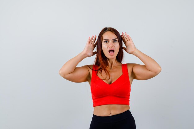 Mulher jovem com cabelo comprido e uma regata laranja