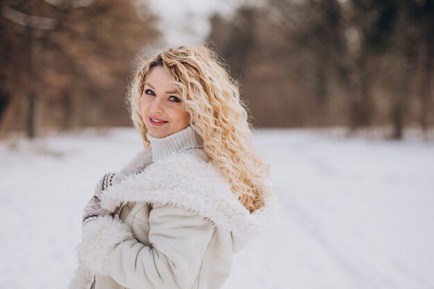 Mulher jovem com cabelo encaracolado caminhando em um parque de inverno