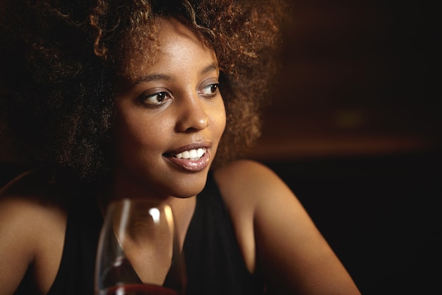 Mulher jovem com cabelo encaracolado e um copo de vinho tinto