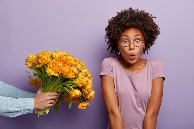 Mulher jovem com cabelo encaracolado recebendo um buquê de flores amarelas