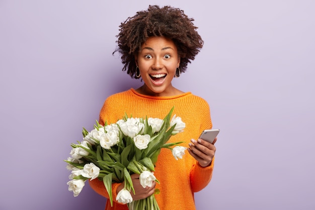 Mulher jovem com cabelo encaracolado segurando um buquê de flores brancas