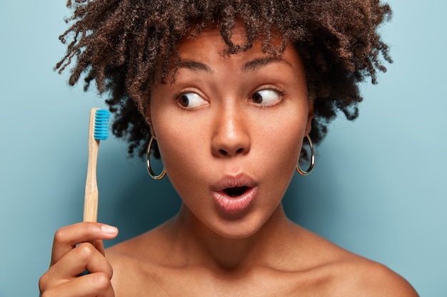 Mulher jovem com cabelo encaracolado segurando uma escova de dentes