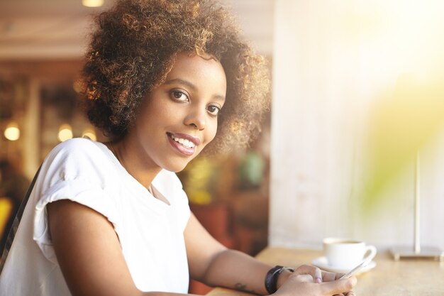 Mulher jovem com cabelo encaracolado sentada num café