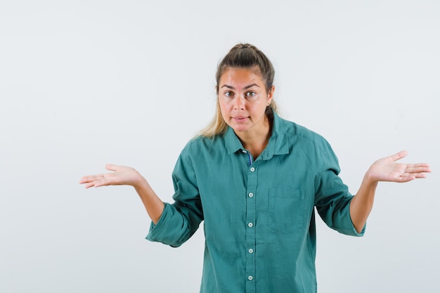 Foto grátis mulher jovem com camisa azul mostrando um gesto desamparado e parecendo descontente