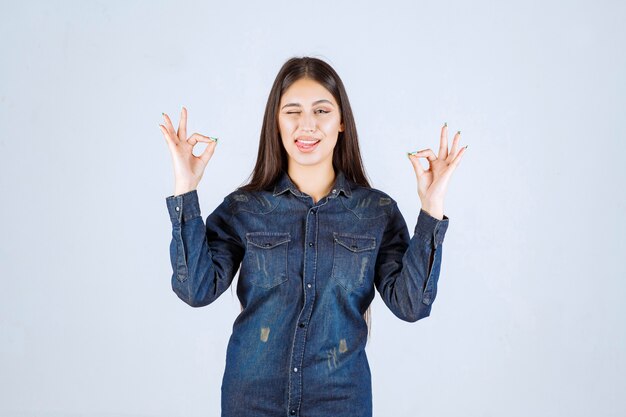 Mulher jovem com camisa jeans mostrando sinal de satisfação