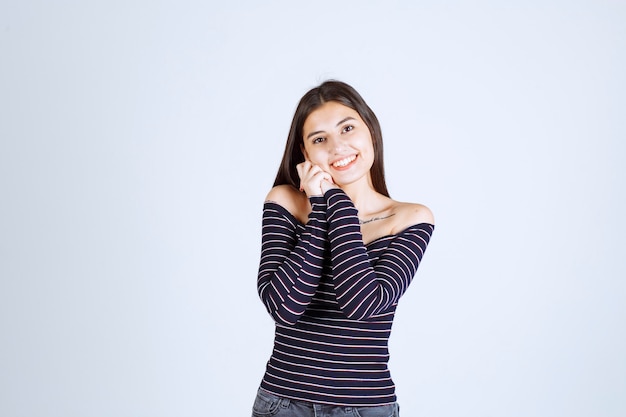 Mulher jovem com camisa listrada, unindo as mãos e fazendo poses lindas