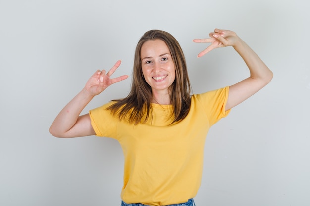 Mulher jovem com camiseta e shorts mostrando um gesto de paz e parecendo alegre