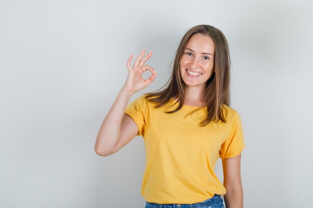 Mulher jovem com camiseta e shorts sorrindo e dando sinal de ok