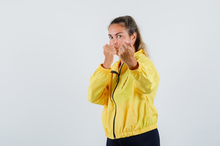 Foto grátis mulher jovem com capa de chuva amarela mostrando os punhos e parecendo poderosa