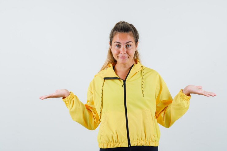 Foto grátis mulher jovem com capa de chuva amarela mostrando um gesto de desamparo