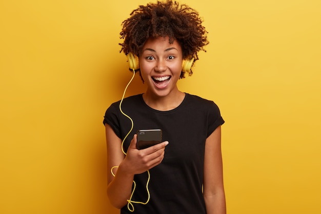 Mulher jovem com corte de cabelo afro com fones de ouvido amarelos