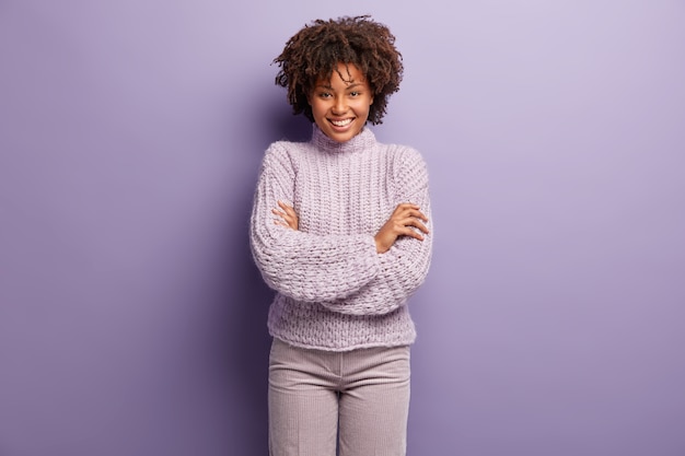 Mulher jovem com corte de cabelo afro e suéter roxo