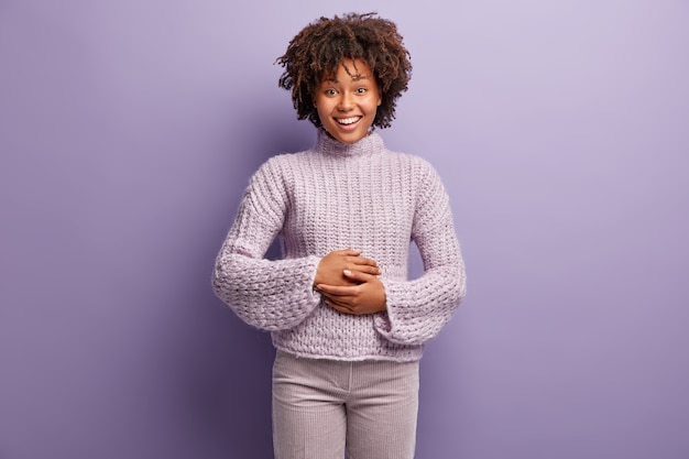 Mulher jovem com corte de cabelo afro e suéter roxo