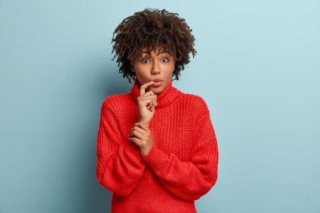 Mulher jovem com corte de cabelo afro e suéter vermelho