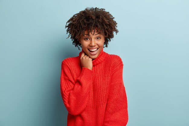 Mulher jovem com corte de cabelo afro e suéter vermelho