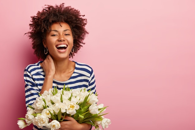 Foto grátis mulher jovem com corte de cabelo afro segurando um buquê de flores brancas