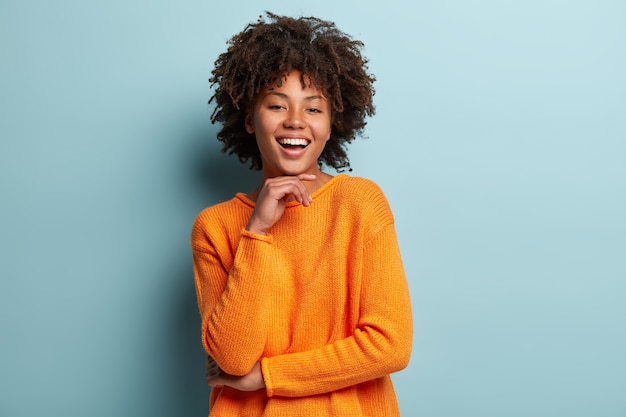 Mulher jovem com corte de cabelo afro usando um macacão laranja