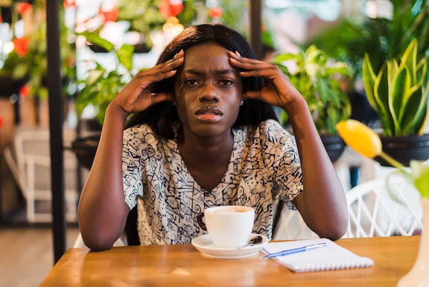 Foto grátis mulher jovem com dor de cabeça enquanto trabalha em um laptop no café