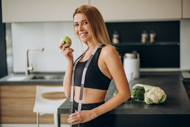 Mulher jovem com fita métrica na cozinha