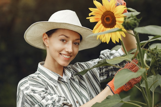 Foto grátis mulher jovem com girassóis. senhora de chapéu. menina em um jardim.