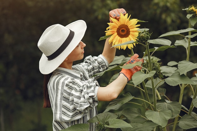 Mulher jovem com girassóis. senhora de chapéu. menina em um jardim.