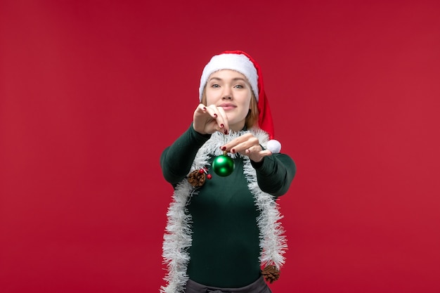 Foto grátis mulher jovem com guirlandas segurando um brinquedo no fundo vermelho