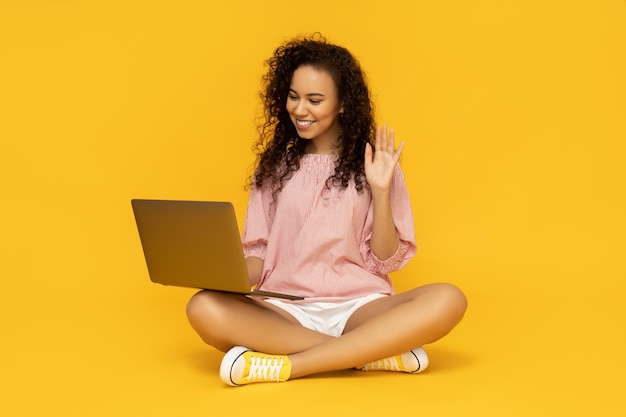 Mulher jovem com laptop em fundo amarelo