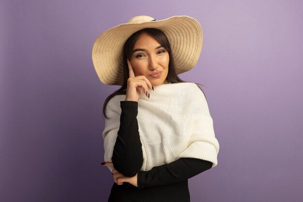 Mulher jovem com lenço branco e chapéu de verão sorrindo confiante