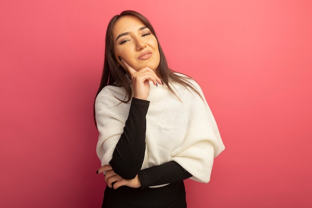 Mulher jovem com lenço branco e mão no queixo sorrindo confiante