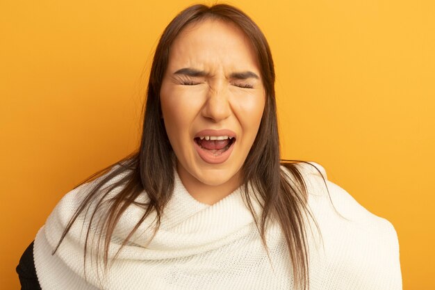 Mulher jovem com lenço branco gritando com expressão irritada com os olhos fechados