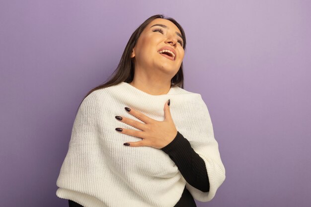 Mulher jovem com lenço branco segurando a mão em seu peito feliz e positiva