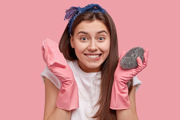 Mulher jovem com lenço na cabeça segurando produtos de limpeza