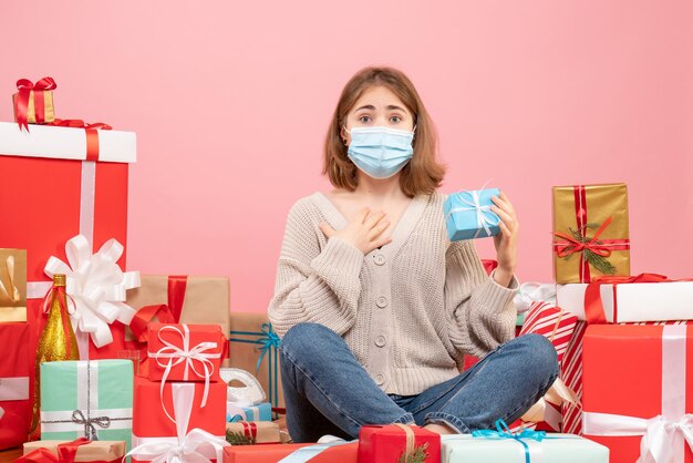 Mulher jovem com máscara sentada de frente em um presente de natal