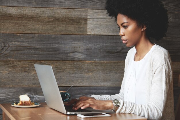 Mulher jovem com penteado afro sentada em um café