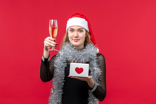 Mulher jovem com presente comemorando na parede vermelha férias de natal