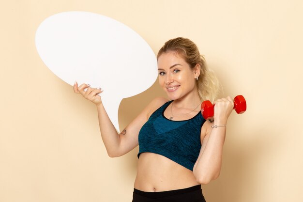 Mulher jovem com roupa esportiva, vista frontal, segurando halteres e balão de fala branco