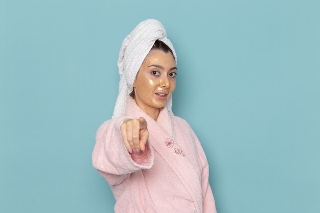 Mulher jovem com roupão rosa após o banho na parede azul beleza banho de água creme autocuidado chuveiro banheiro